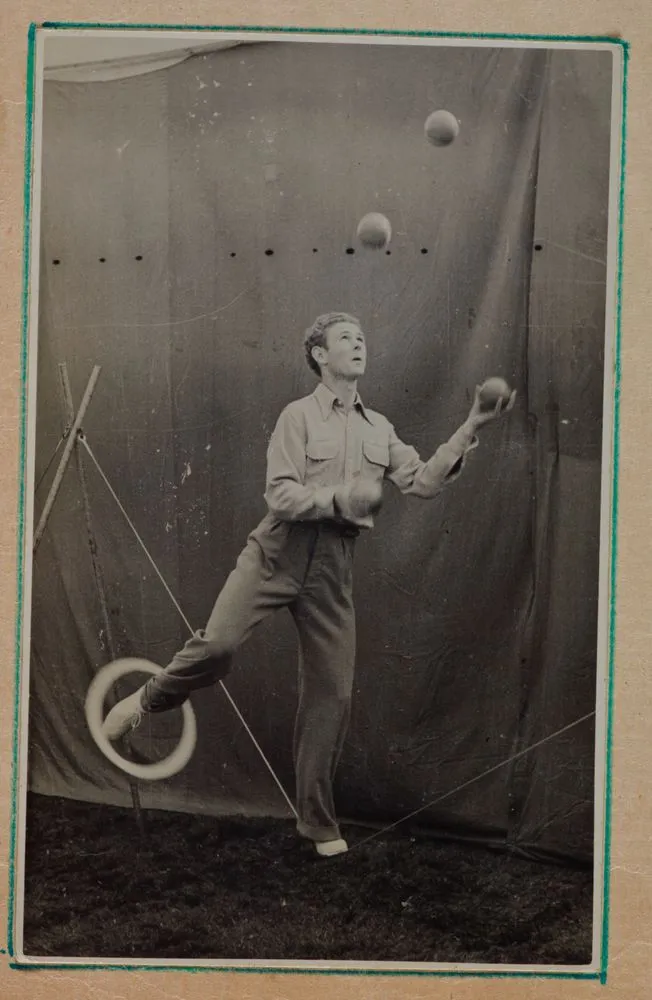 [man juggling balls, while spinning ring on foot]