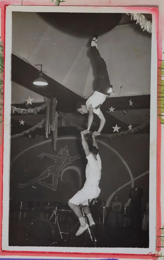 [two men performing acrobatic tricks on a unicycle]