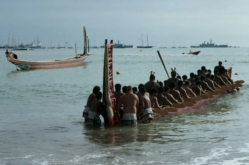 Men launching a waka into harbour
