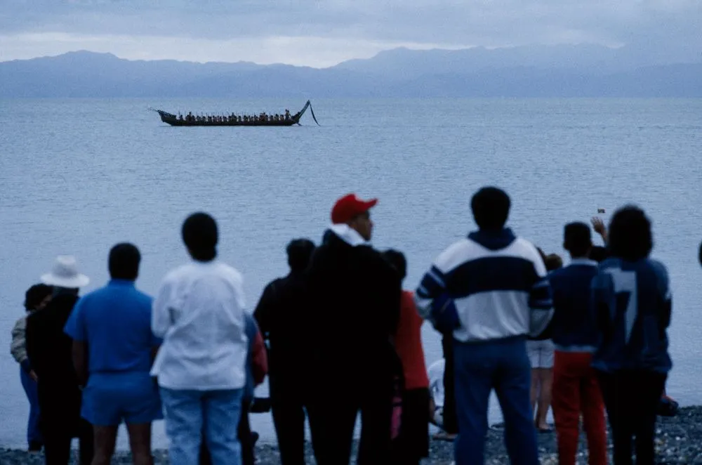 Group watching a waka taua (war canoe) in harbour