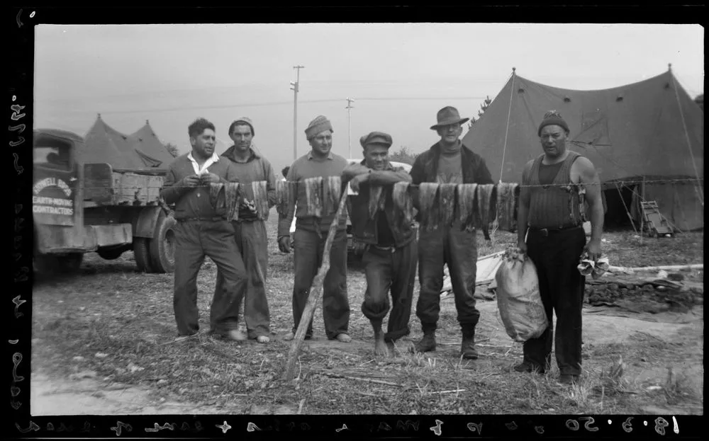 Group of cooks at Raukawa marae where the centenary celebrations continued. Line with dried eels in front. [Centenary celebrations of founding of Rangiātea Church]