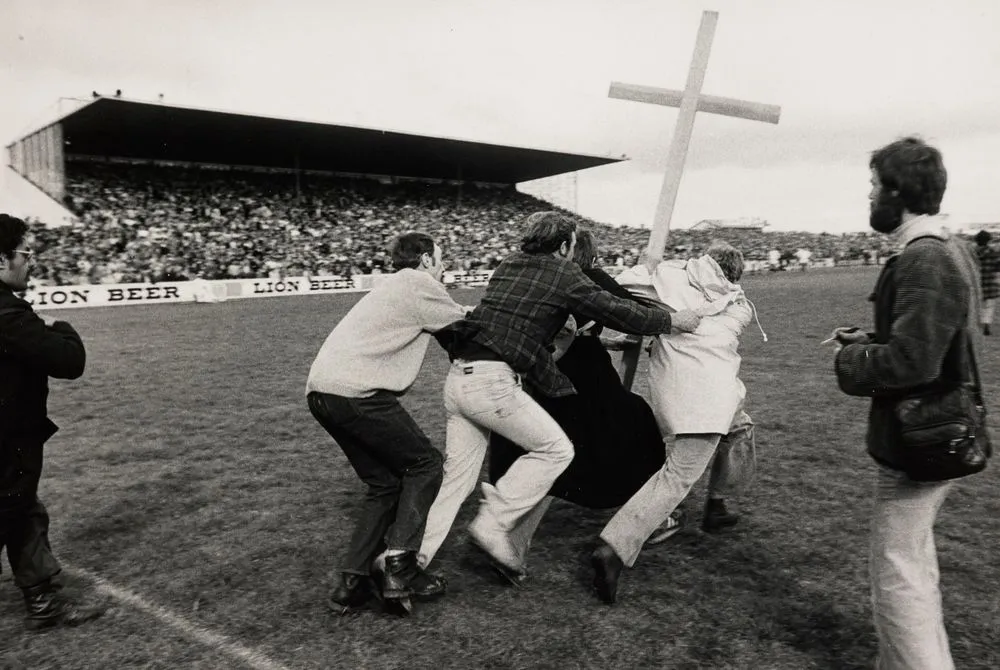 Two members of St John's College run onto Rugby Park, Hamilton, while two supporters of Springbok Rugby Tour try to stop them, 1981