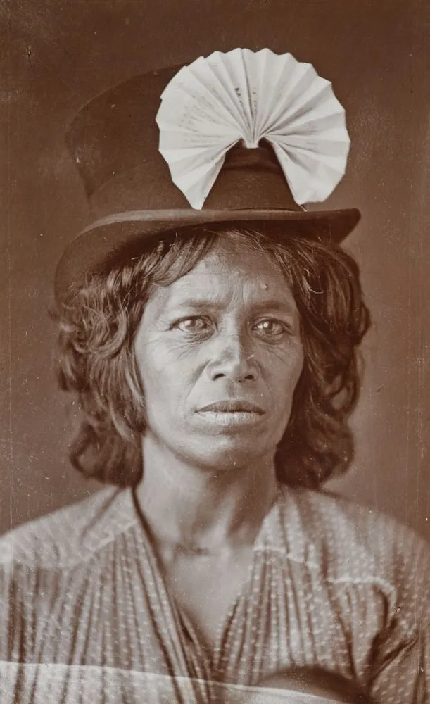 Maori woman wearing top hat and paper fan