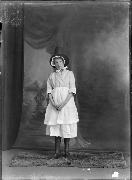 Studio portrait of unidentified young woman in costume, with milking maid's clothing with bonnet and pilgrim's hat, Christchurch