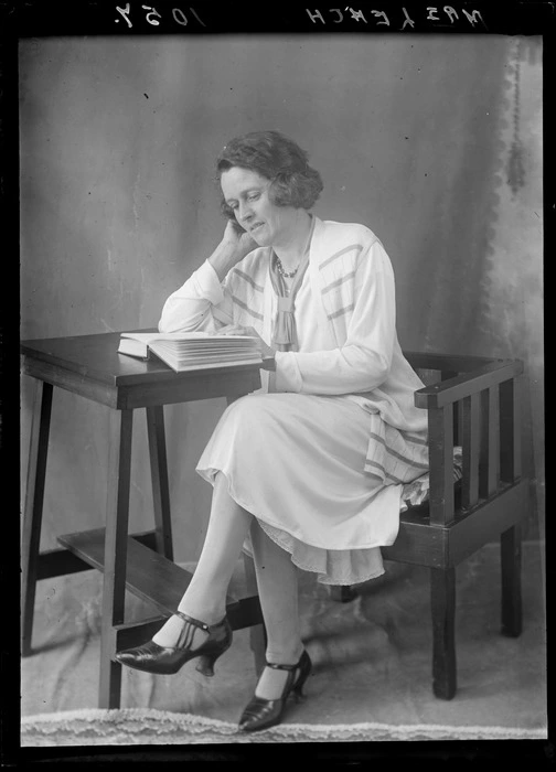 Mrs Leach from Hastings reading a book seated at a small table