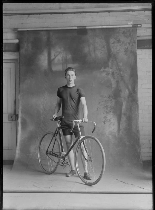 Unidentified young man with racing bicycle in front of backdrop, probably Christchurch