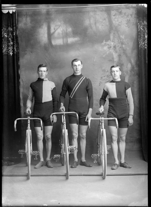 Studio portrait of three unidentified male cyclists, in uniform with racing bicycles, probably Christchurch district