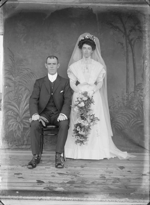 Unidentified wedding couple outdoors, with a painted studio backdrop, probably Christchurch district
