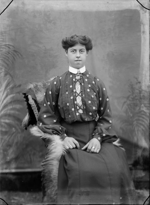 Studio portrait of unidentified woman, wearing a polka dot blouse and tie, probably Christchurch district