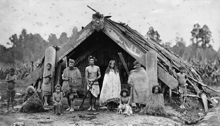 Bragge, James, 1833?-1908 : Maori family outside a whare puni, Mangaakuta, near Masterton
