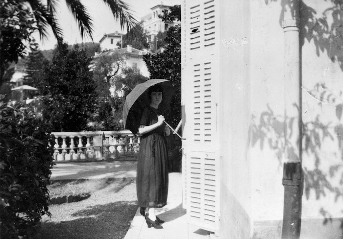 Katherine Mansfield standing with a parasol by the Villa Isola Bella, France