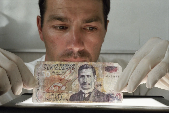 Detective Constable Tim Crawford with fake $50 note - Photograph taken by Ross Giblin