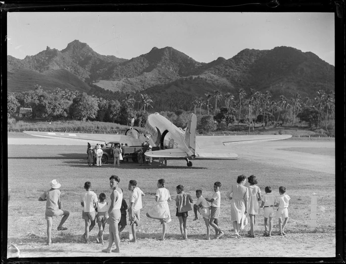 C47 aircraft at Rarotonga airfield, Cook Islands, includes local island children in the foreground