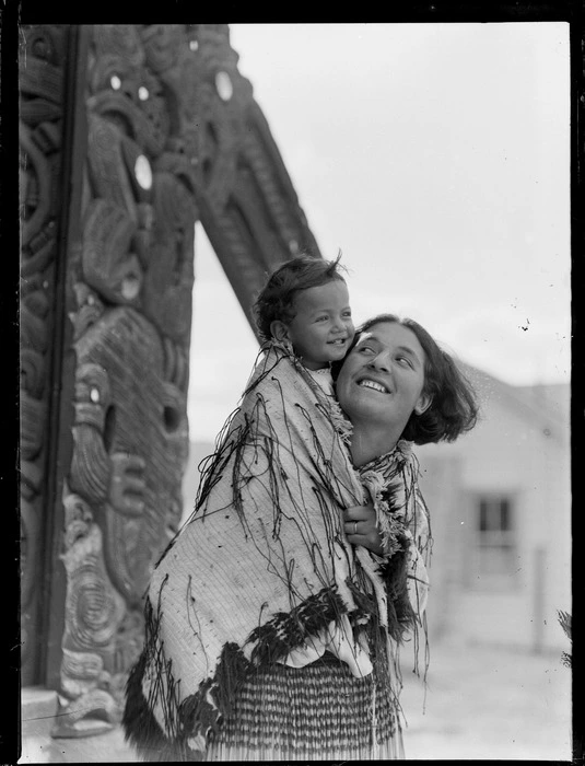 Kahu Morrison and baby, outside a marae wharenui (meeting house)