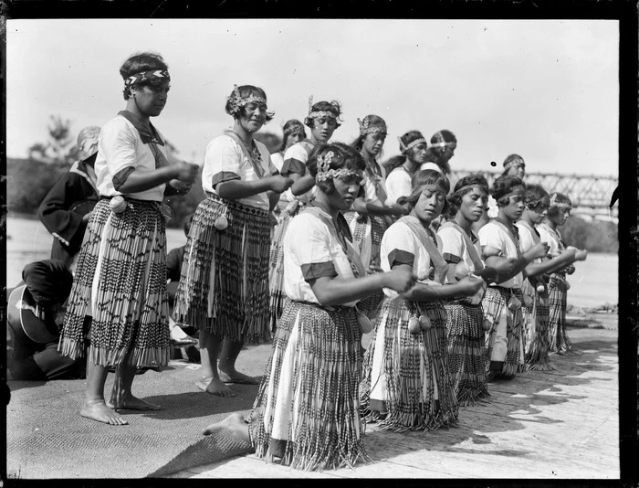 Unidentified Maori women dancing, includes traditional dress (piupu), head bands with taniko design and poi