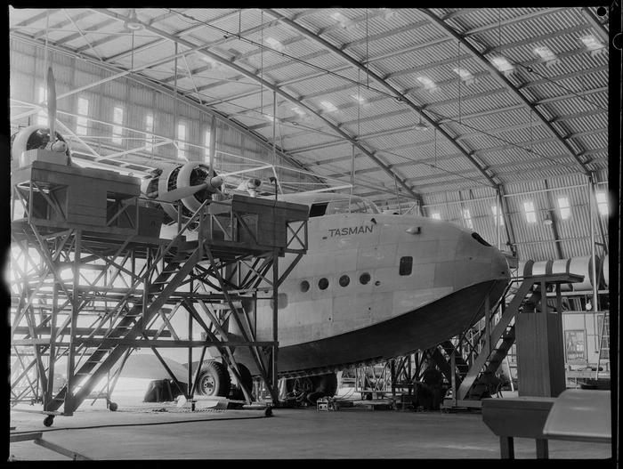 Side and nose view of a Short Tasman aircraft, in a workshop, Hobsonville, Auckland, including scaffolding
