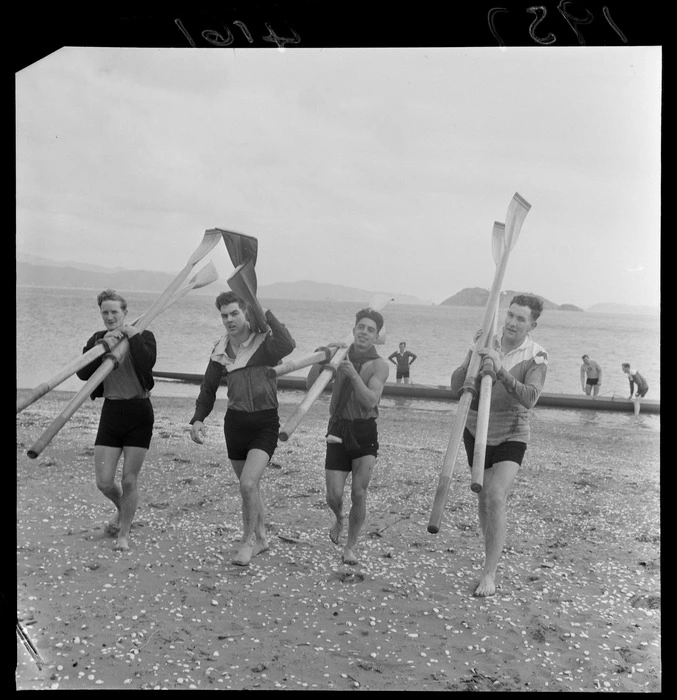 Four unidentified rowers carrying oars, on beach at Petone, Lower Hutt City