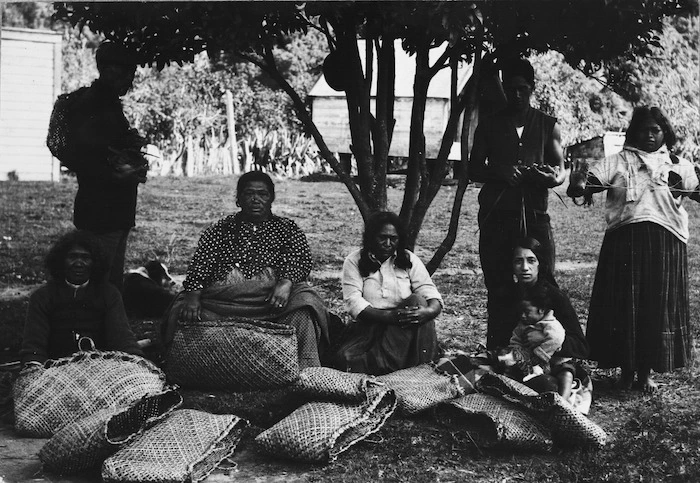 Group of men and women with kete and other items made from flax