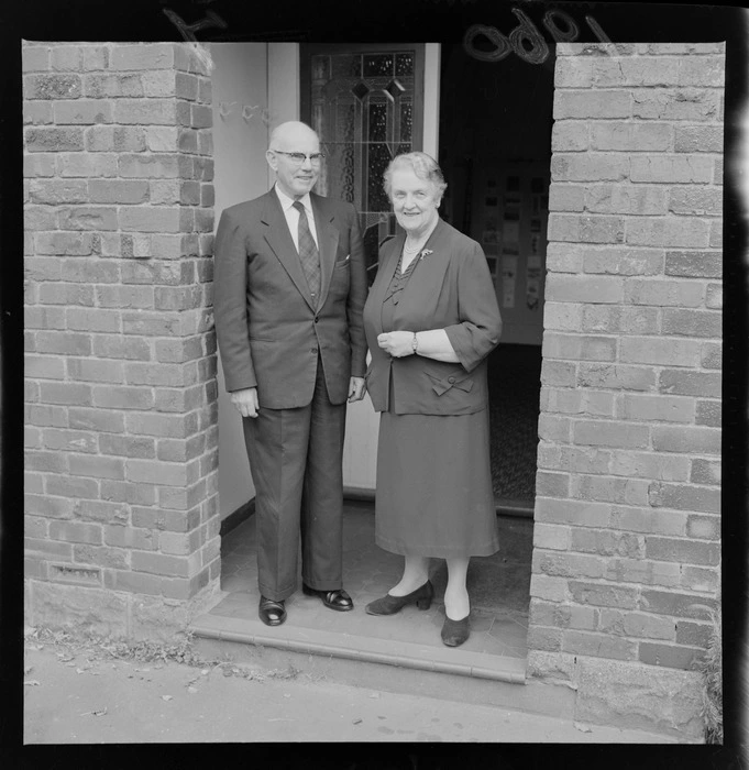 Sir George and Lady Currie standing by the front door of their home, location unknown, Wellington Region