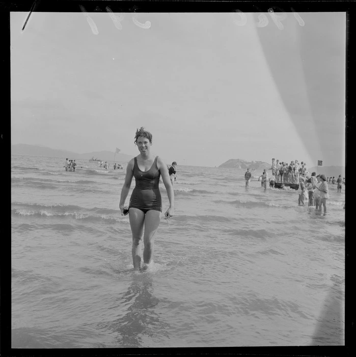 An unidentified young woman who just completed the Somes Island Petone swim on Petone Beach with children looking on, Wellington City