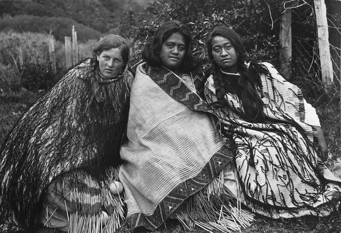 Three women wearing flax cloaks