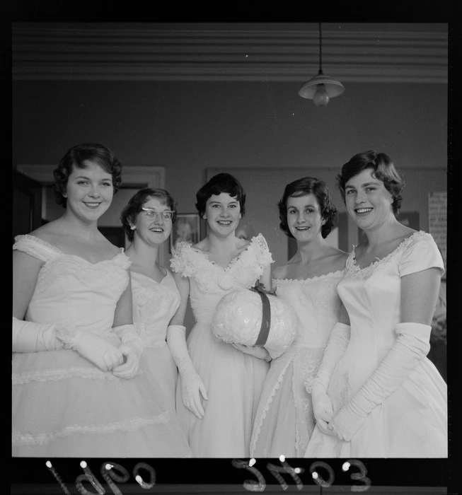 Group portrait of debutante girls in evening dresses with lucky snowball for the Plunket Ball, probably Wellington Region