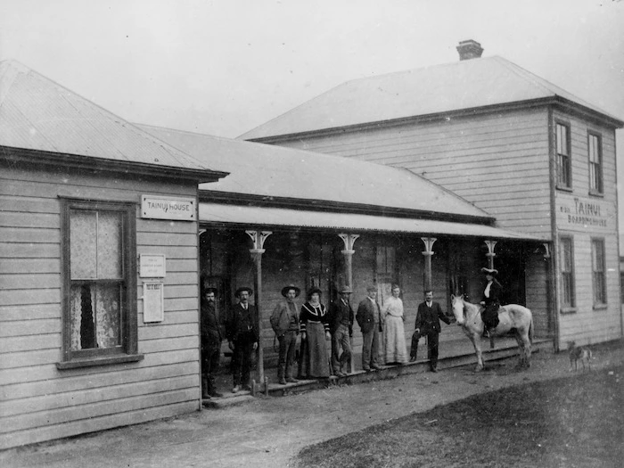 Tainui Boarding House, Mokau, with a group on the verandah