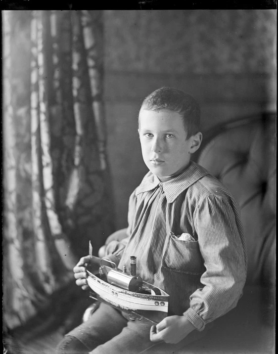 Owen William Williams, with a model ship of the 'Apollo', probably at his home, Royal Terrace, Kew, Dunedin