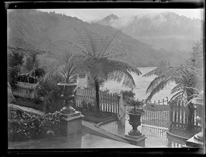 View down to the front entrance of Pipiriki House with stairs, potted plants and garden on a bank above the Whanganui River, Pipiriki