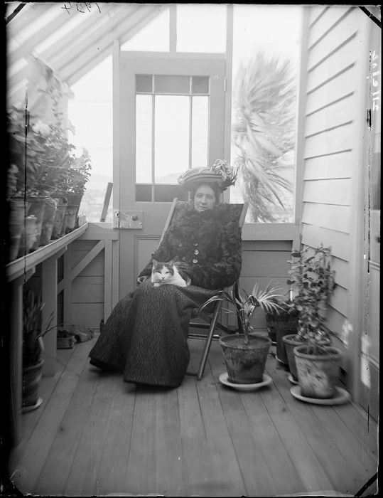 Nellie Devereux with cat on lap, sitting in conservatory at Royal Terrace, Kew, Dunedin