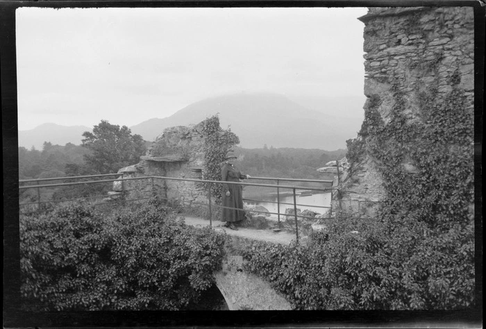 Lydia Williams standing on ramparts of castle ruins, looking out towards lake and mountains, Killarney, County Kerry, Ireland