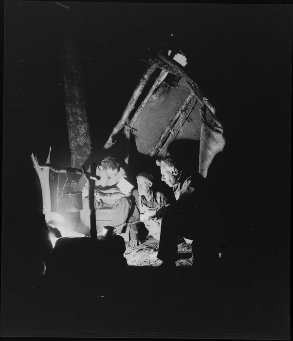 Three men, [including Edgar Williams?], sitting around a campfire at night, probably West Coast Region