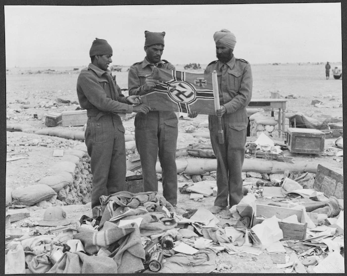 Members of the Indian Army holding a Nazi flag in an evacuated German camp in Libya, during World War 2