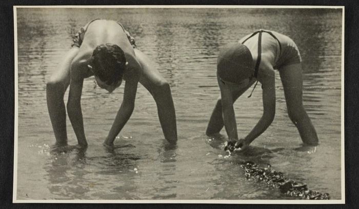 Two children wearing swimming costumes in shallows