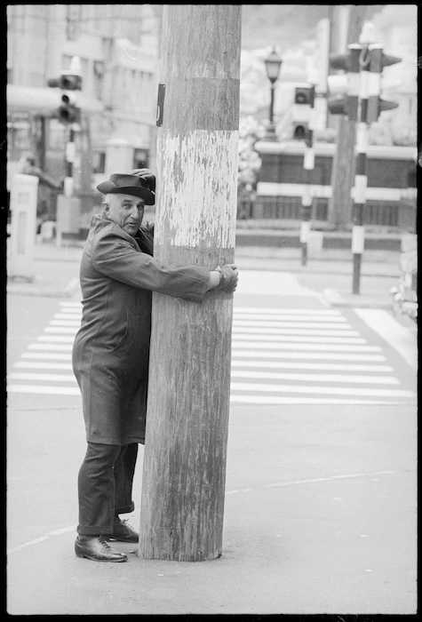 Man hugging a power pole at the intersection of Courtenay Place and Taranaki Street, Wellington