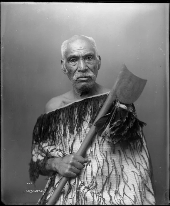 Maori man wearing korowai and carrying a tewhatewha