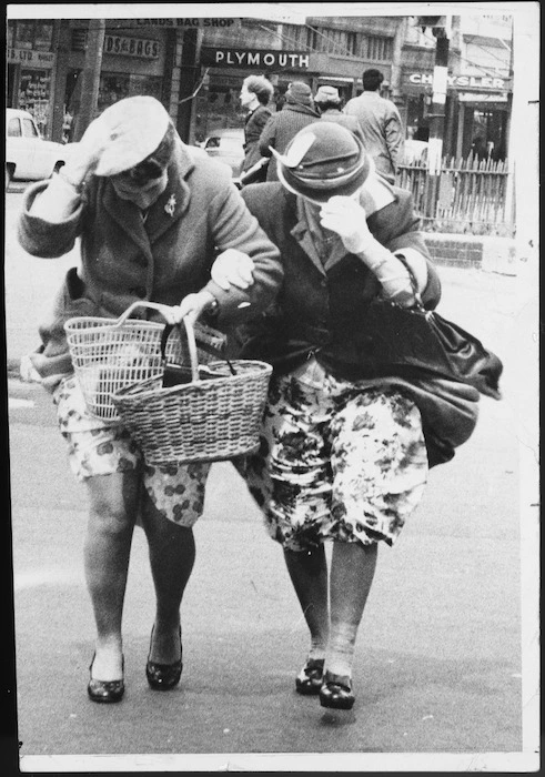 Women battling against the wind while crossing a Wellington city street