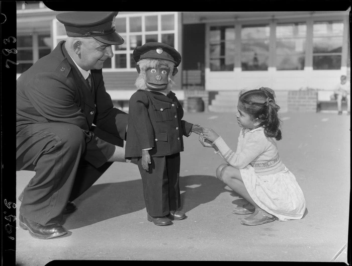 Traffic officer Mr TW Jeffreys [Jeffries?] and doll Safety Charlie, with unidentified girl at Mount Cook School, Wellington