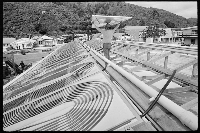 Solar heating panels, and installer Colin Doughty, on the roof of the Eastbourne swimming pool, Lower Hutt - Photograph taken by Merv Griffiths