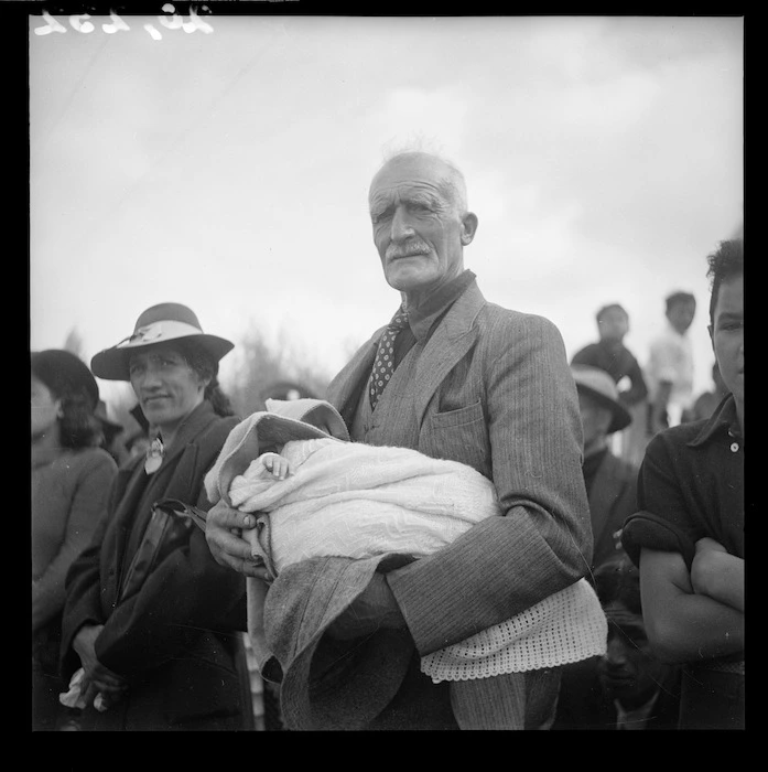Koroua holding a baby at the opening of Tawakeheimoa meeting house at Te Awahou Marae, Lake Rotorua