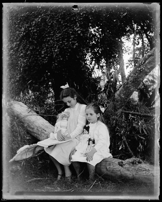 Two young girls sitting on a tree trunk