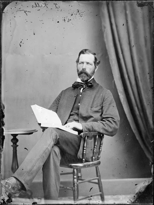 Mr Kells, seated, with an open book