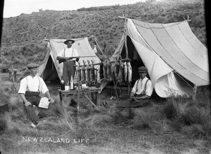 Men at their camp site displaying a catch of rabbits and fish