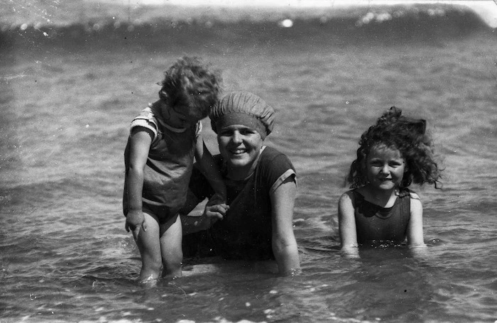 A women and two children, wearing swimming costumes in the sea