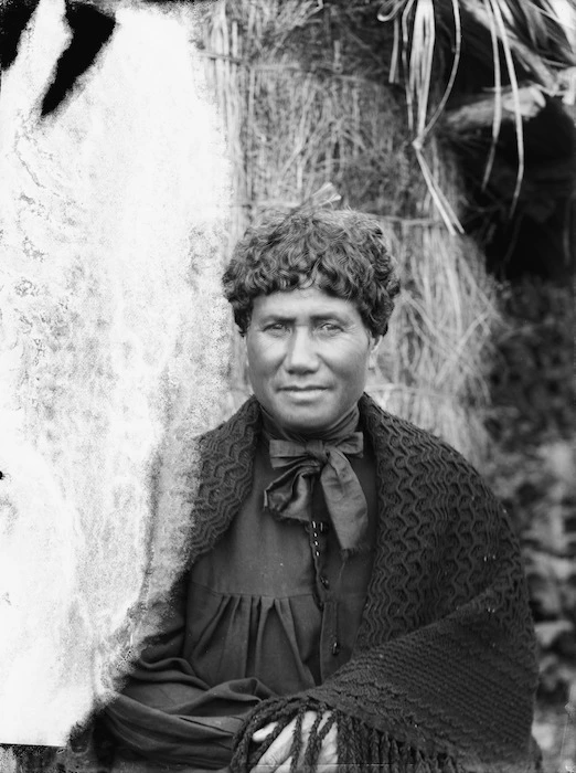 Portrait of Heeni Te Rei standing in front of a whare at Karaka Bay, Wellington