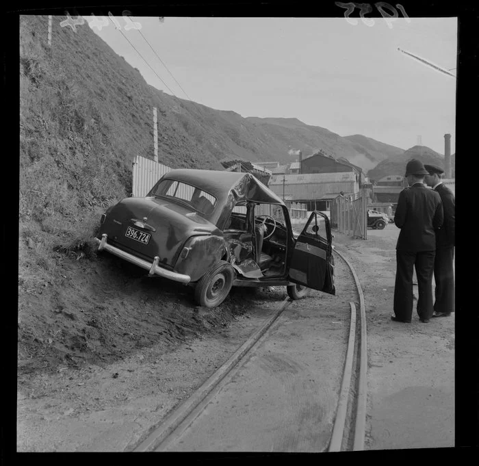 Unidentified police officers looking at a Humber motorcar that has been in an accident, Ngauranga Freezing Works, Wellington