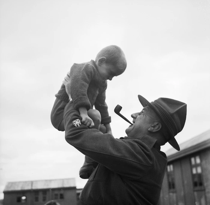 Soldier holding up a young child in a Polish camp, Pahiatua
