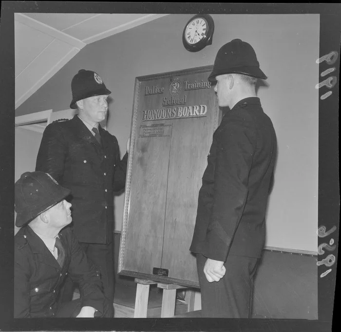 Group of unidentified policemen standing next to the Police Training School honours board, Trentham, Upper Hutt