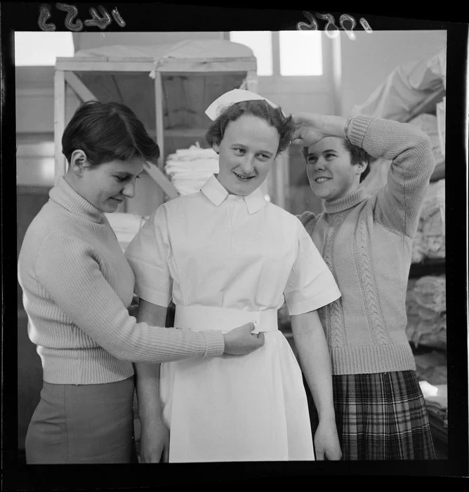 Two student nurses dress a nurse in uniform at Wellington hospital