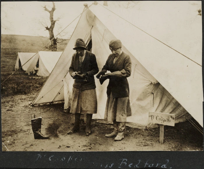 Doctor Cooper and Miss Bedford cleaning boots outside a tent, Serbia.